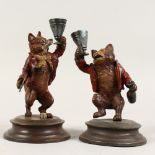 A PAIR OF PAINTED BRONZE CANDLESTICKS, modelled as a bear and fox. 7ins high.