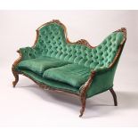 A VICTORIAN WALNUT FRAMED DOUBLE CAMEL BACK SETTEE, upholstered in green velvet, with two loose