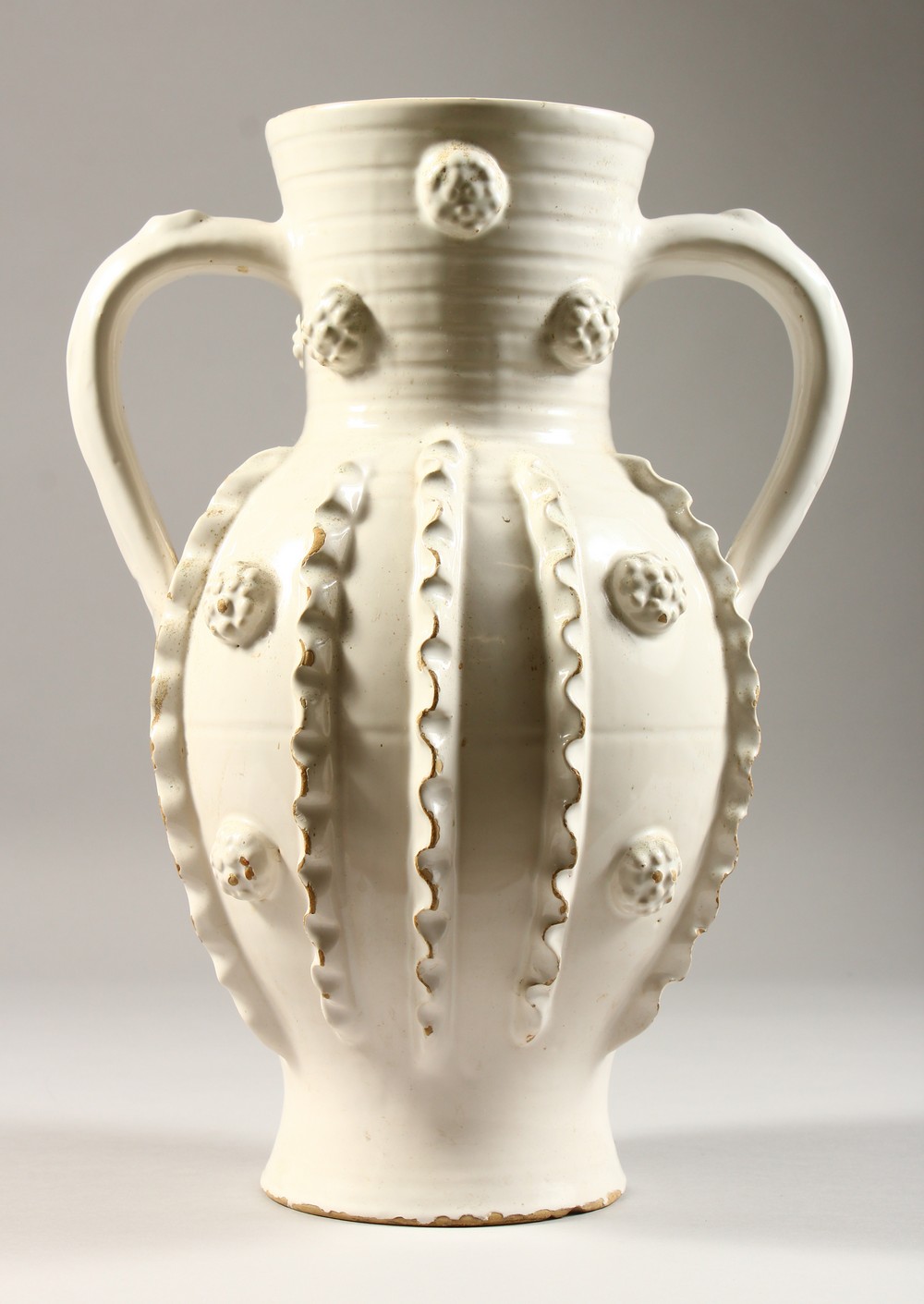 A 20TH CENTURY CONTINENTAL WHITE GLAZED TWIN HANDLED EARTHENWARE VASE, with ribbed decoration. 13ins