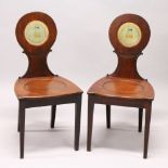 A GOOD PAIR OF REGENCY MAHOGANY HALL CHAIRS, the oval backs painted with a family crest, with
