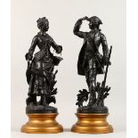 A PAIR OF SPELTER FIGURES, a man holding a gun,, a lady with a basket, on turned wooden bases. 19ins