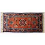 A CHINESE RUG, with terracotta ground and coloured motifs. 5ft x 2ft 4ins.