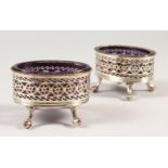 A PAIR OF OLD SHEFFIELD PLATE PIERCED SALTS with amethyst coloured glass liners. 3ins wide.