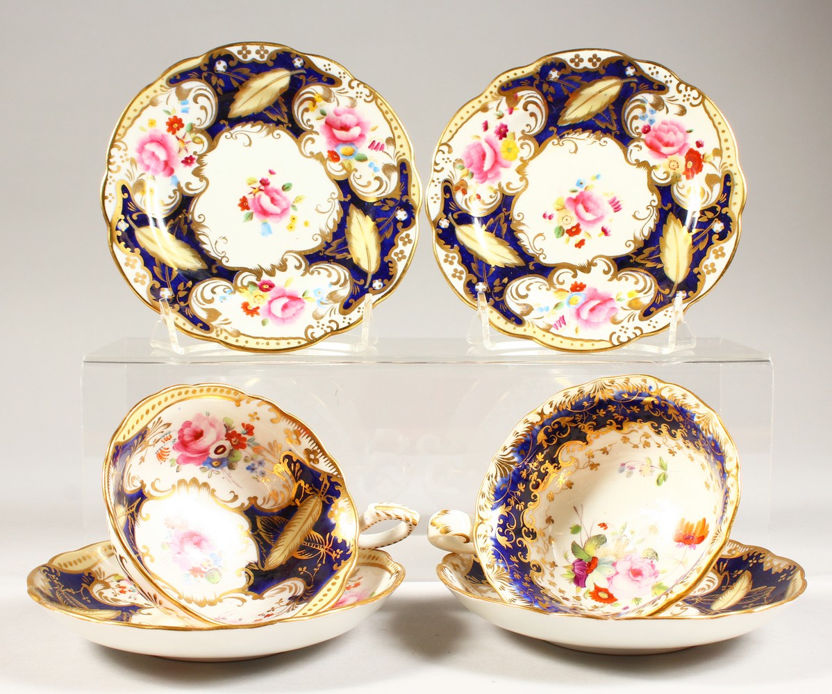 TWO COALPORT PORCELAIN TRIOS, blue and gilt decorated with roses.