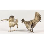 A PAIR OF CAST SILVER MODELS OF FIGHTING COCKERELS. 8ins high.