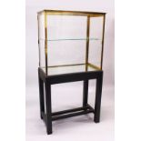 A GOOD BRASS FRAMED DISPLAY CASE, glazed all round, with a single glass shelf, on an ebonised stand.