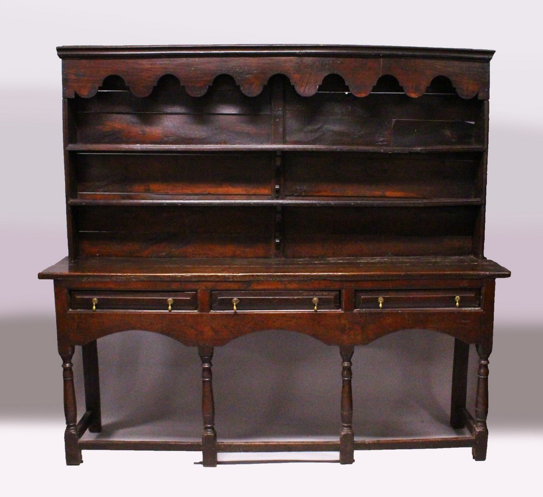 AN EARLY 17TH CENTURY OAK DRESSER, the upper section with shaped pelmet, and two shelves, the twin