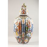 A LARGE CONTINENTAL POLYCHROME DECORATED TIN GLAZE RIBBED JAR AND COVER, decorated in the
