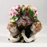 A CONTINENTAL STYLE JARDINIERE, modelled as two children hiding beneath a flower. 8.5ins high.