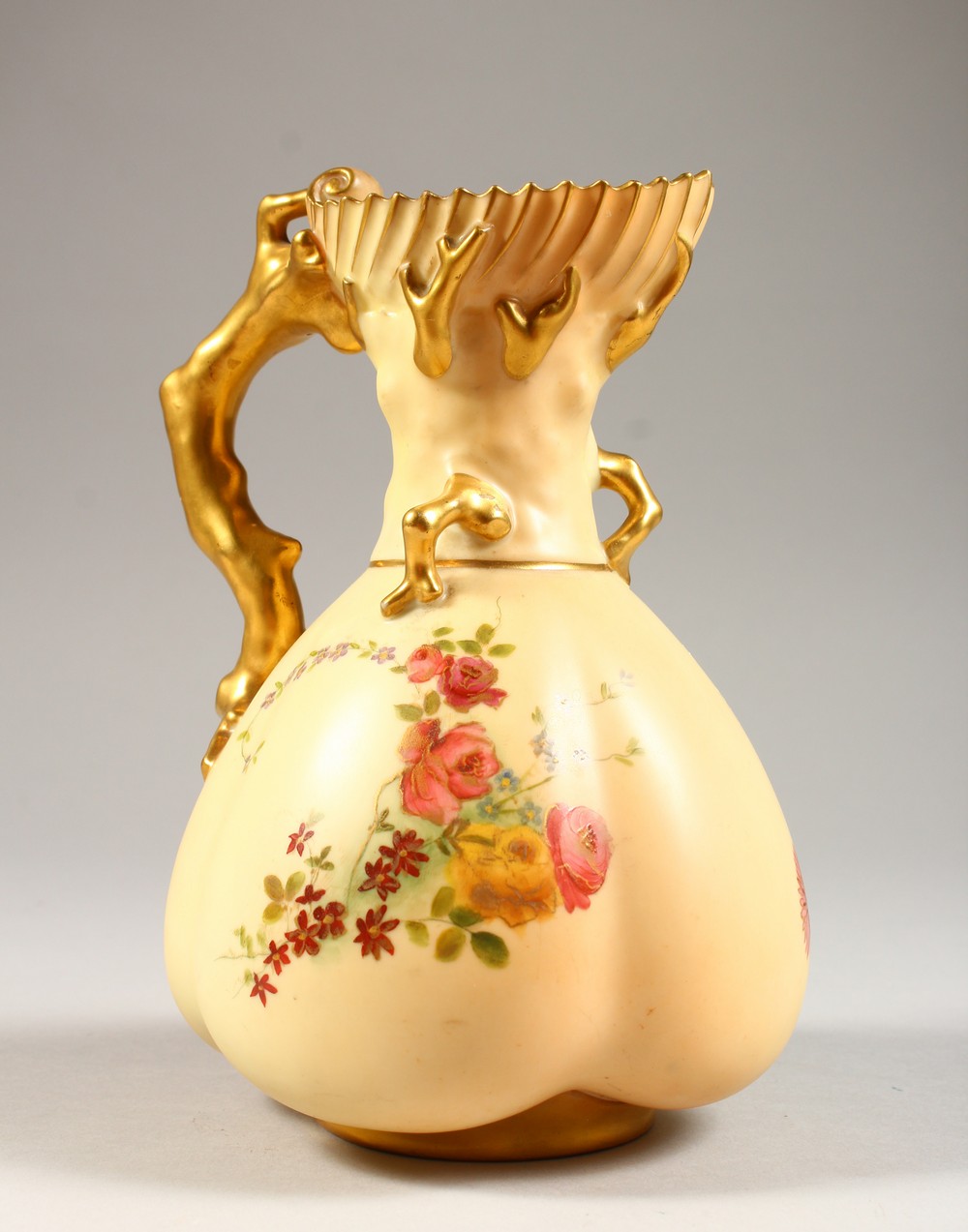 A ROYAL WORCESTER BLUSH IVORY JUG, No. 1507 with naturalistic handle and floral decoration. 7ins