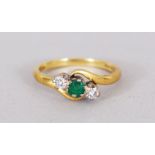 AN 18CT GOLD, DIAMOND AND EMERALD CROSSOVER RING.
