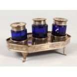 AN OLD SHEFFIELD PLATE INK STAND, with three blue glass bottles, pierced sides on curving feet. 7ins