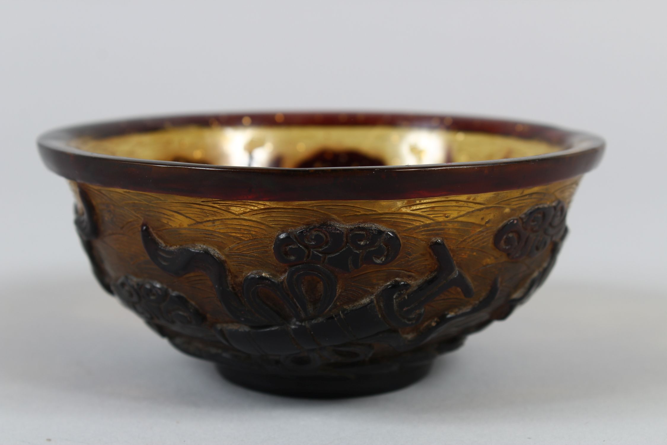 A CHINESE PEKING AMBER GLASS RICE BOWL, with gilt speck inclusions, carved decoration of four Taoist - Image 4 of 7