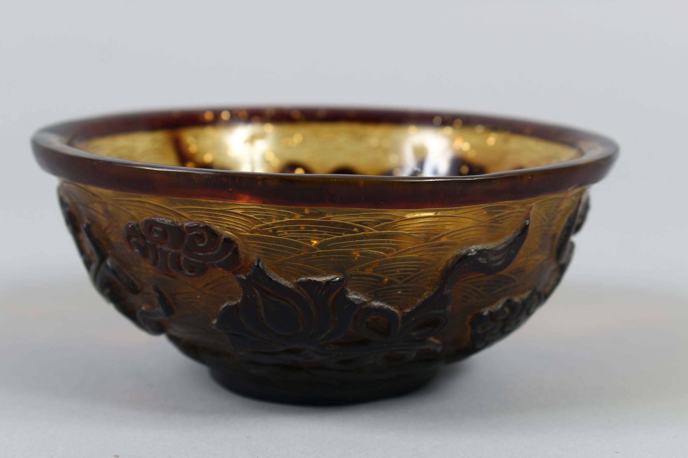 A CHINESE PEKING AMBER GLASS RICE BOWL, with gilt speck inclusions, carved decoration of four Taoist - Image 3 of 7