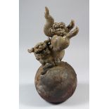A JAPANESE POTTERY MODEL OF A FOO DOG ON A BALL, square seal signature to rear, Meiji period, 35cm