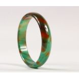 A CHINESE JADE LIKE GLASS BANGLE, of striated green and russet colouring, 7.9cm diameter.