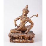 A THAI GILT BRONZE FIGURE OF A SEATED MUSICIAN / GOD / GODDESS, sat upon a plinth playing a sung,