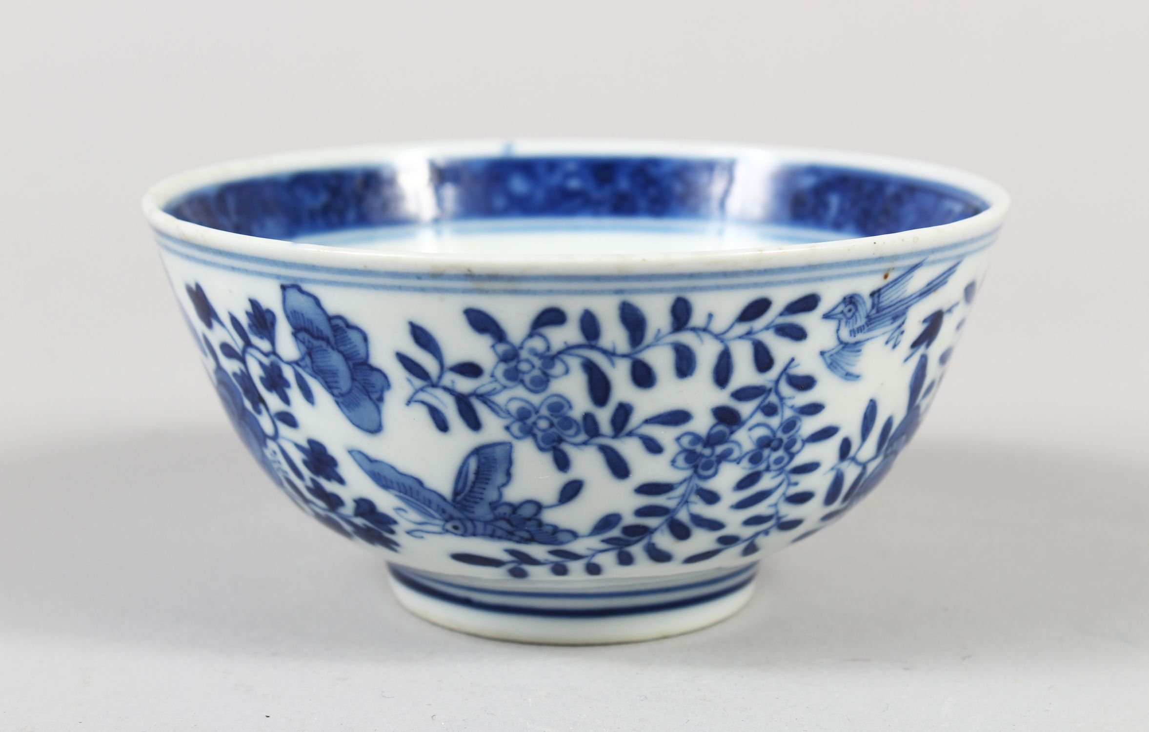 A CHINESE BLUE AND WHITE PORCELAIN BOWL, decorated with butterflies, birds amongst flora, 6cm