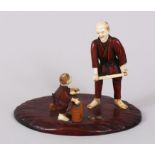 A GOOD JAPANESE IVORY AND WOOD OKIMONO GROUP OF A FATHER AND SON, father stood holding an implement,