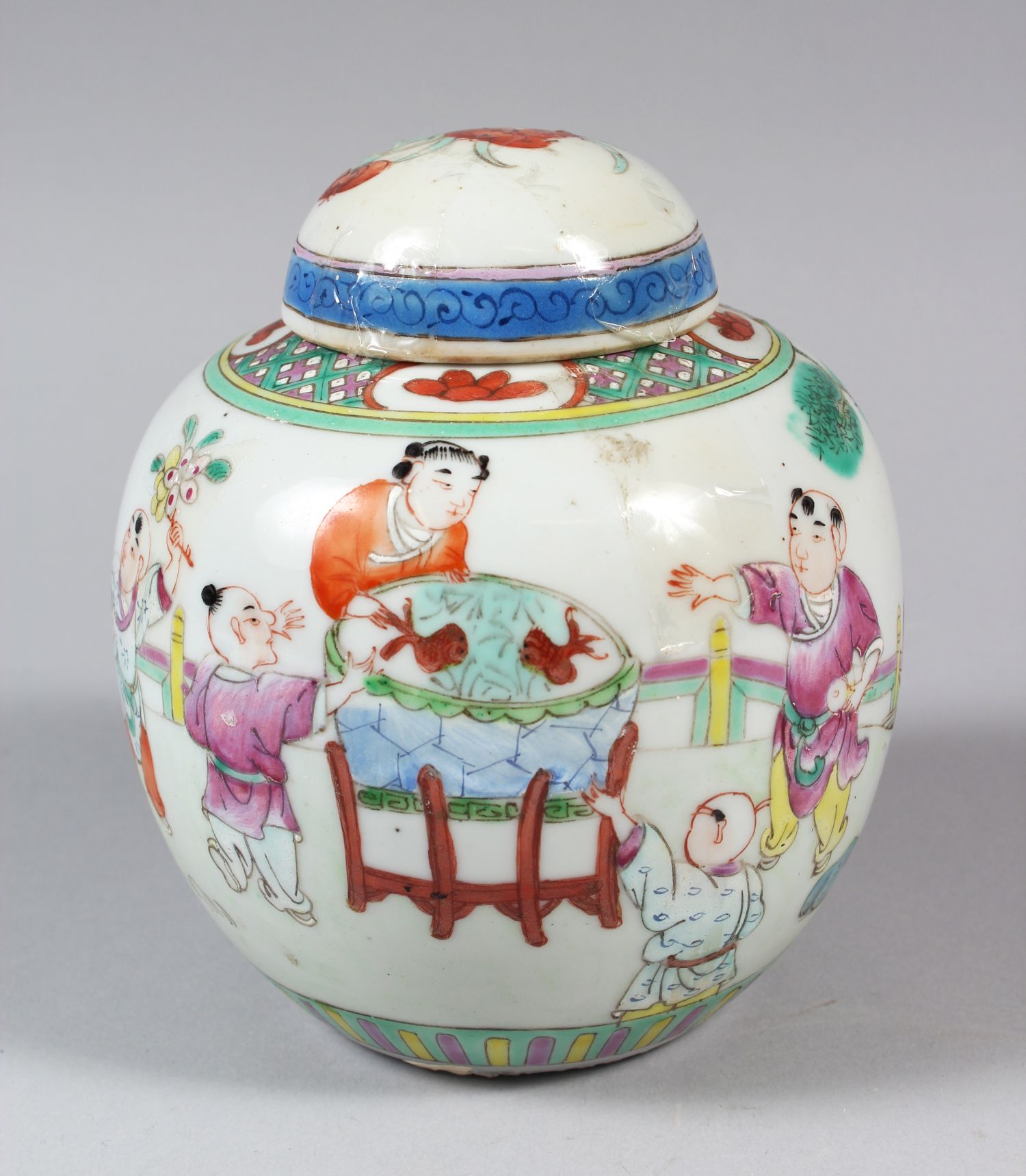 A CHINESE WUCAI GINGER JAR WITH COVER, decorated with parading people, surrounding a fishbowl