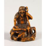 A JAPANESE BOXWOOD NETSUKE, depicting a seated sage upon a rock, Meiji period, artist signed to