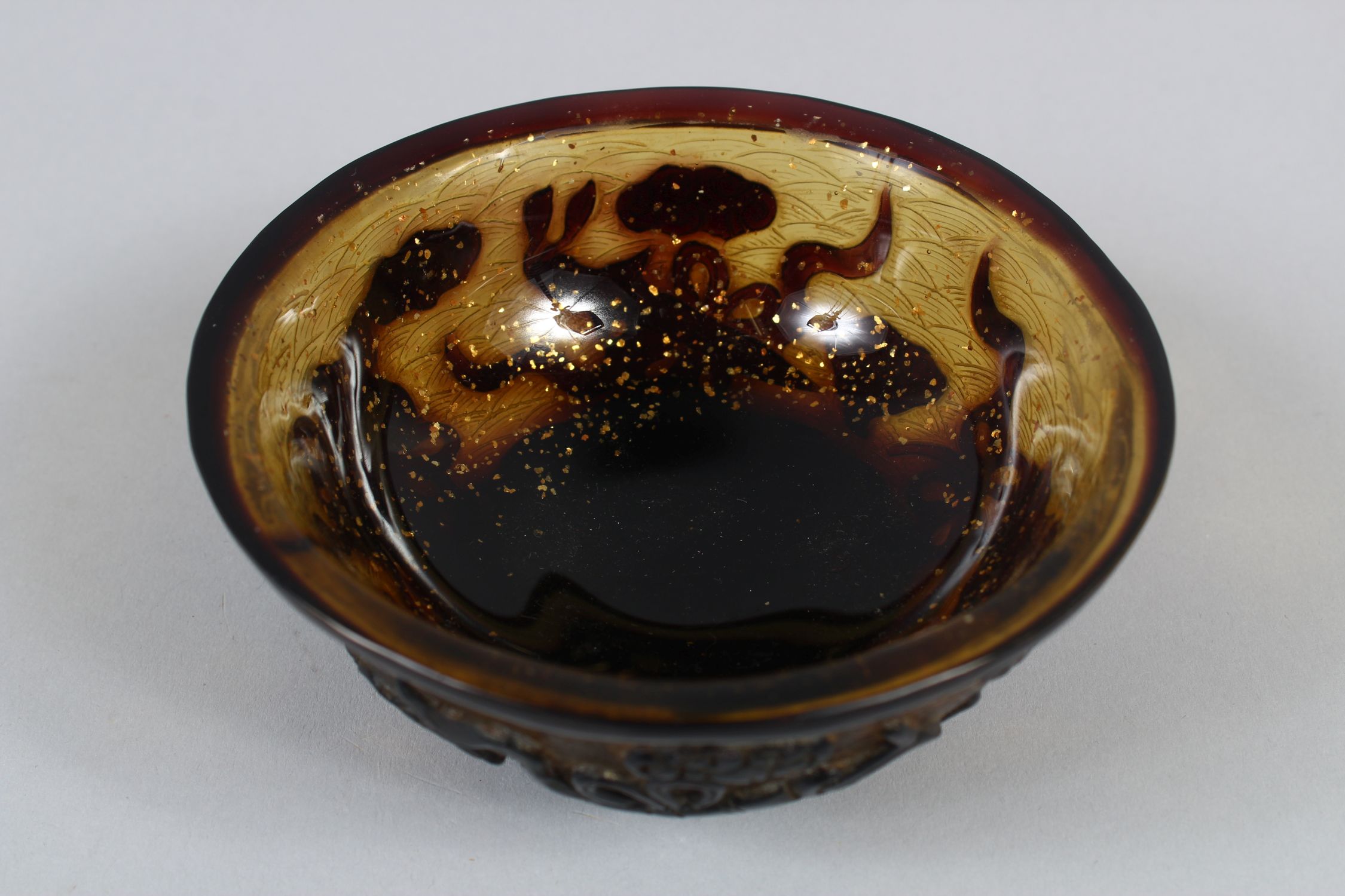 A CHINESE PEKING AMBER GLASS RICE BOWL, with gilt speck inclusions, carved decoration of four Taoist - Image 5 of 7