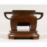 A CHINESE HEAVY BRONZE TWIN-HANDLED CENSER, of rounded rectangular form, on a base. 15cms wide.