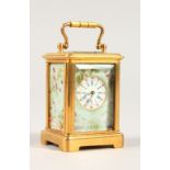 A MINIATURE CARRIAGE CLOCK, with brass case and decorative porcelain panels. 5.5cms high.