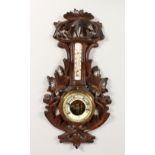 A CARVED WOOD THERMOMETER BAROMETER. 18ins long.