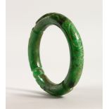 A CHINESE GREEN JADE BANGLE, with carved decoration. 8.5cms diameter.