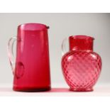 TWO VICTORIAN RUBY GLASS JUGS. 21cms and 18cms high.