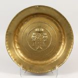 AN EARLY BRASS ALMS DISH, repousse with Adam & Eve. 41cms diameter.