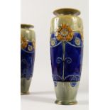 A LARGE PAIR OF ROYAL DOULTON STONEWARE VASES, with green flowers on a blue band. 35cms high.