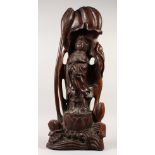 A LARGE CHINESE CARVED WOOD FIGURE OF GUANYIN, standing within a lotus plant. 73cms high.