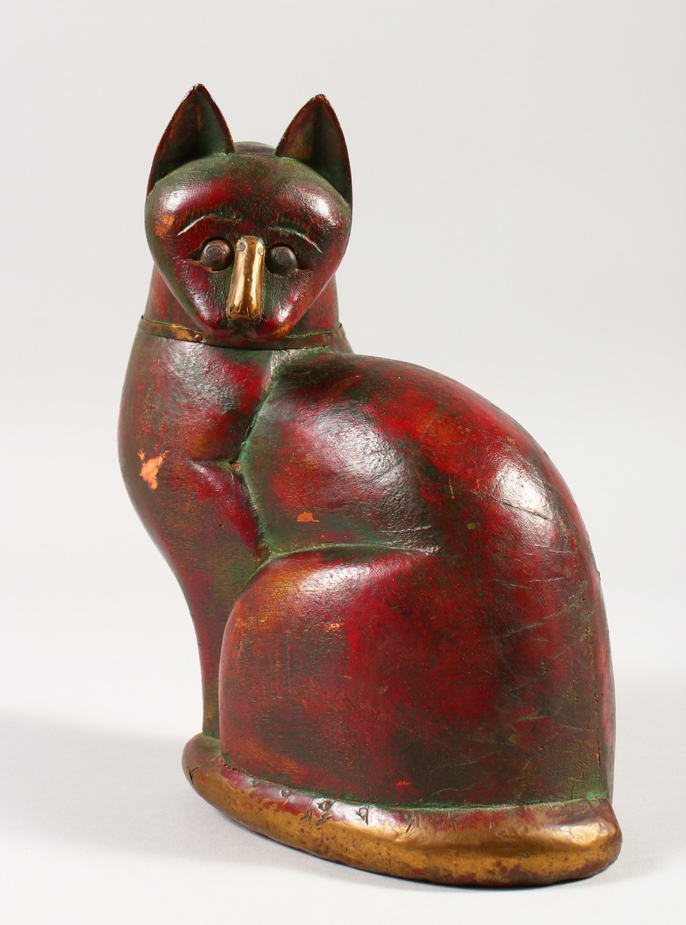 AN ISLAMIC CARVED SEATED CAT with brass nose, collar and bone. 21cms high.