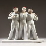 AN ART DECO DESIGN BLUE AND WHITE GROUP OF THREE SAILORS with red pom pom hats. 11ins high.