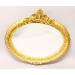 A FRENCH STYLE GILTWOOD OVAL WALL MIRROR, with decorative cresting. 100cms wide x 90cms high.