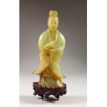 A CHINESE JADE CARVING OF GUANYIN, on a carved wood base. 28cms high.