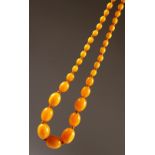 AN AMBER BEAD NECKLACE. Largest bead 2.5cms long. Overall length 68cms.