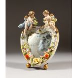 A SMALL DRESDEN STYLE OVAL FLOWER ENCRUSTED EASEL MIRROR with two cupids. 20cms high.