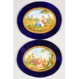 A PAIR OF OVAL PORCELAIN PANELS, rich blue borders, the centre painted with a shepherdess and sheep,