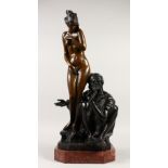 A BRONZE GROUP OF A SEATED ARAB, a young lady stood by his side, on a marble base. 67cms high.