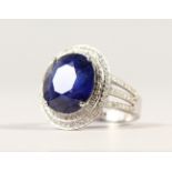 A 14K WHITE GOLD AND DIAMOND RING, set with an oval cut blue sapphire approx. 6.50ct, diamonds