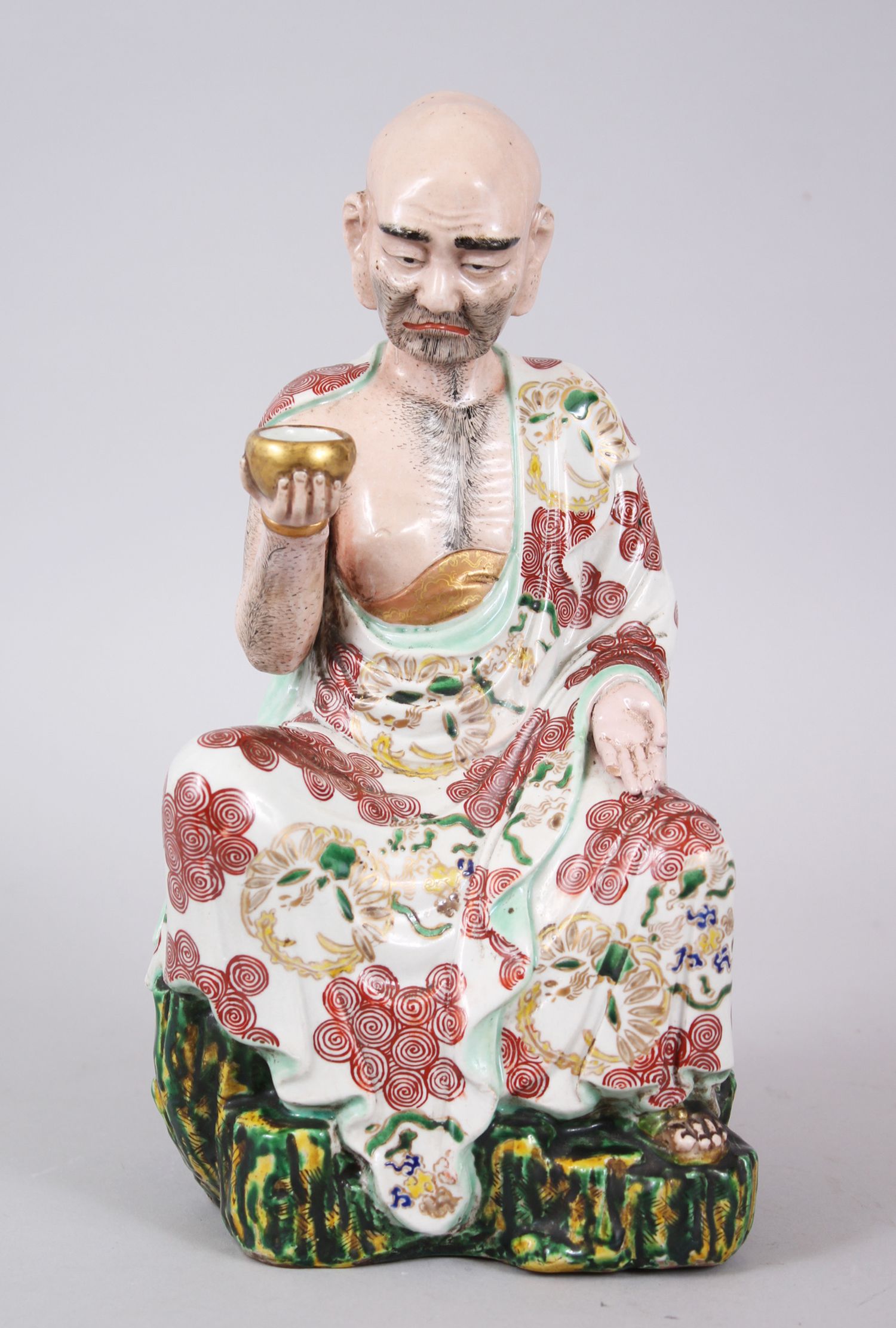 A GOOD JAPANESE KUTANI PORCELAIN MODEL OF AN ARHAT, the arhat with a low expression upon his face,