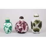 THREE CHINESE PEKING GLASS SNUFF BOTTLES, each decorated with scenes of flora, 8cm high, 6.5cm high,