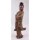AN EARLY CHINESE CARVED WOOD FIGURE OF GUANYIN, stood with her hands crossed holding a scroll,
