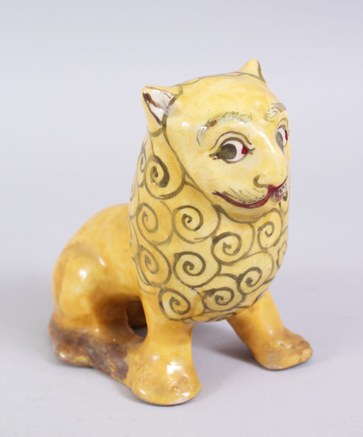 A 19TH CENTURY YELLOW GLAZED PERSIAN LION, with stylized painted mane design, 14cm high x 14,5cm