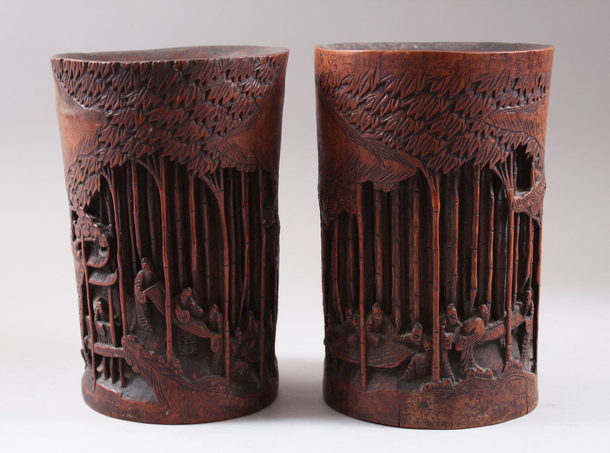 A PAIR OF CHINESE 19TH CENTURY BAMBOO CARVED BRUSH POTS, carved deeply to depict scenes of figures