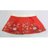 A CHINESE RED EMBROIDERED TEXTILE / SILK SKIRT, with embroidered scenes of birds amongst native