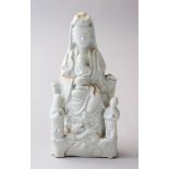 AN 18TH CENTURY CHINESE BLANC DE CHINE PORCELAIN FIGURE OF GUANYIN WITH BOYS, 18.5cm high x 9cm